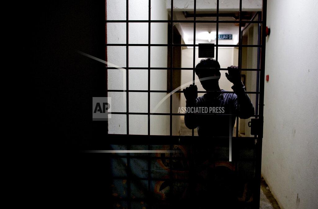 Gemunu Amarasinghe Sayed, a member of Myanmar's long-persecuted Rohingya minority, stands behind a metal door at the entrance of a friend's house in peninsular Malaysia on Monday, April 1, 2019. Sayed is part of an invisible workforce, made up of millions of poor laborers from across Asia, many of whom face exploitation and abuse in both Malaysia and neighboring Indonesia. Together, the two countries produce an estimated 85 percent of the world's $65 billion palm oil supply. (AP Photo/Gemunu Amarasinghe)