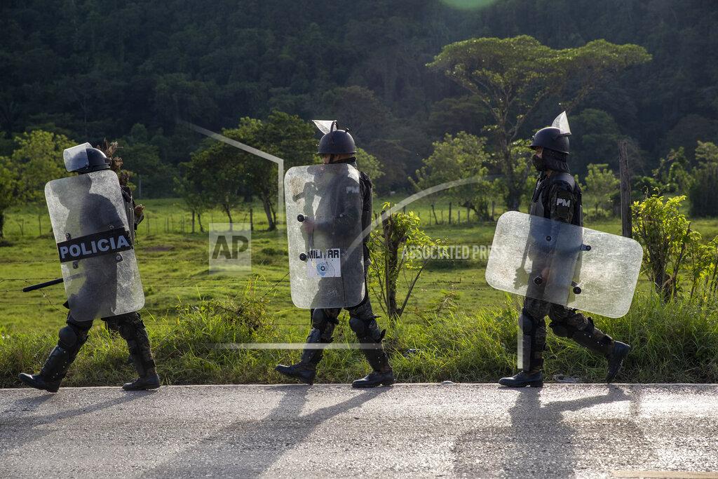 Moises Castillo Security forces block Honduran migrants in San Luis Peten, Guatemala, Saturday, Oct. 3, 2020. Early Saturday, hundreds of migrants who had entered Guatemala this week without registering were being bused back to their country's border by authorities after running into a large roadblock. (AP Photo/Moises Castillo)
