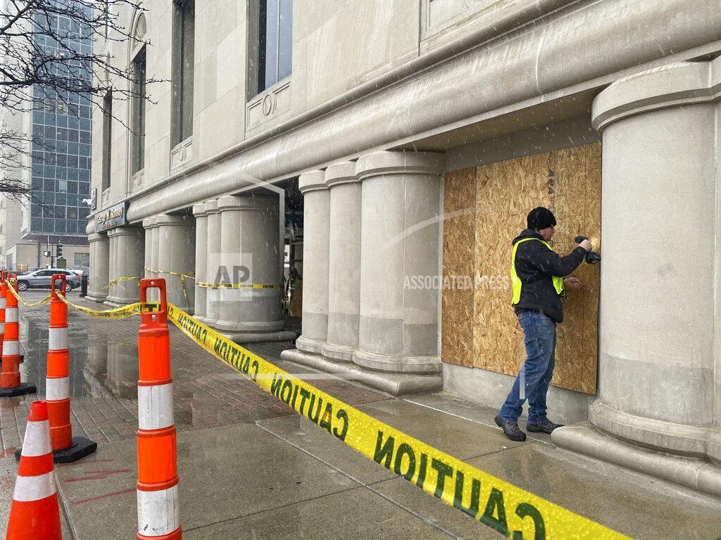 Workers board up the George Romney State Office Building, Friday, Jan. 15, 2021, in Lansing, Mich., in preparation of potential protests ahead of President-elect Joe Biden's inauguration. Gov. Gretchen Whitmer's office is located in the Romney Building. (Matthew Dae Smith/Lansing State Journal via AP)