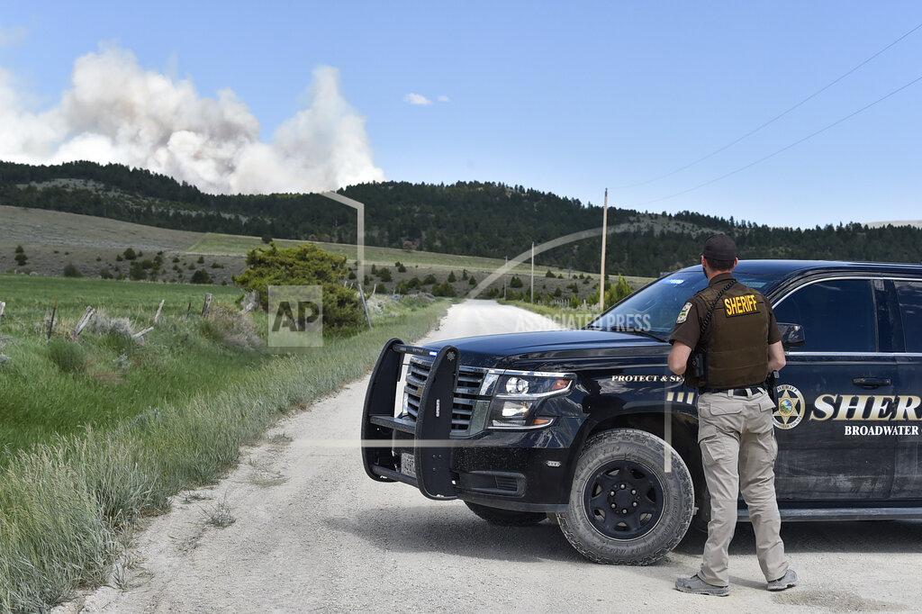 Thom Bridge A Broadwater County Sheriff's deputy runs a roadblock as the Deep Creek Canyon fire burns outside Townsend, Mont., Tuesday, June 15, 2021. (Thom Bridge/Independent Record via AP)
