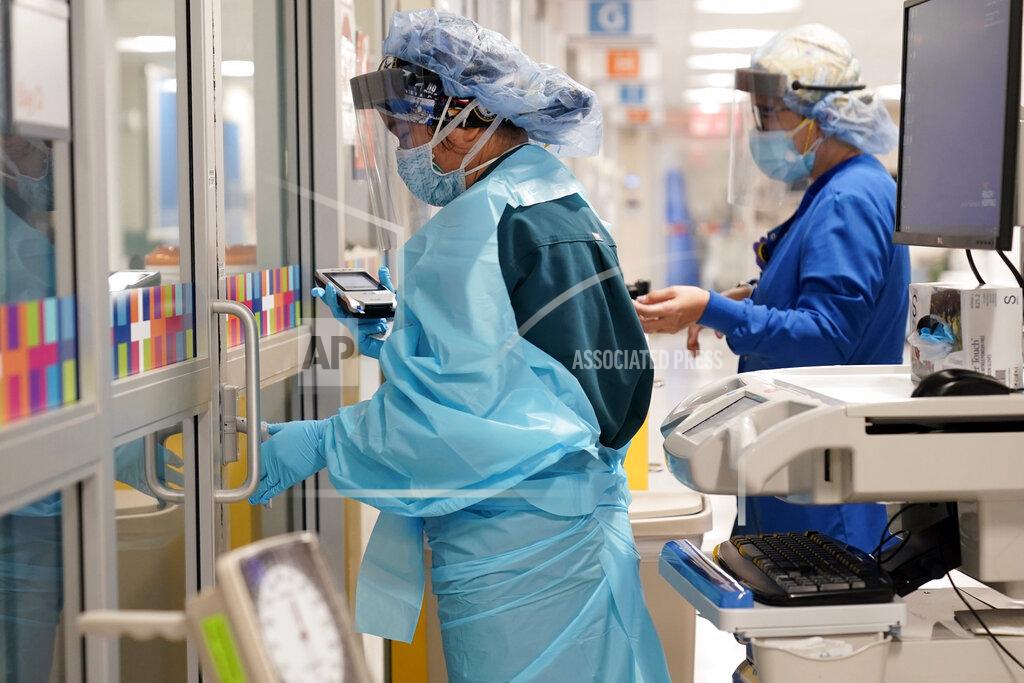 Seth Wenig FILE - In this Oct. 28, 2020, file photo, medical personnel don PPE while attending to a patient (not infected with COVID-19) at Bellevue Hospital in New York. Workers in New York City-run hospitals and health clinics will have to get vaccinated or get tested weekly under a policy announced Wednesday, July 21, 2021, to battle a rise in COVID-19 cases fueled by the highly contagious delta variant. (AP Photo/Seth Wenig, File)