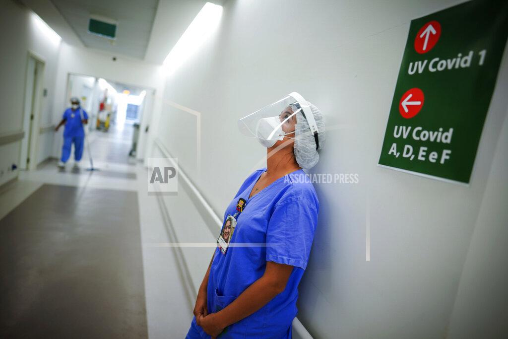 Jefferson Bernardes FILE - In this March 19, 2021 file photo, a healthcare worker lends against a wall in the corridor of an ICU unit for COVID-19 patients at the Hospital das Clinicas, in Porto Alegre, Brazil. The withdrawal of generous pandemic welfare payments comes at a time when there is no near-term hope of mass vaccination to safeguard the labor force. (AP Photo/Jefferson Bernardes, File)