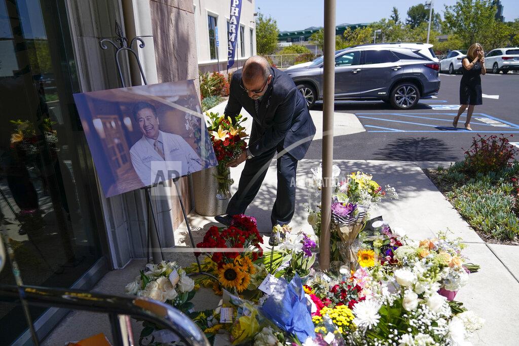 Ashley Landis A man places flowers at a memorial honoring Dr. John Cheng sits outside his office building on Tuesday, May 17, 2022, in Aliso Viejo, Calif. Cheng, 52, was killed in Sunday's shooting at Geneva Presbyterian Church. (AP Photo/Ashley Landis)