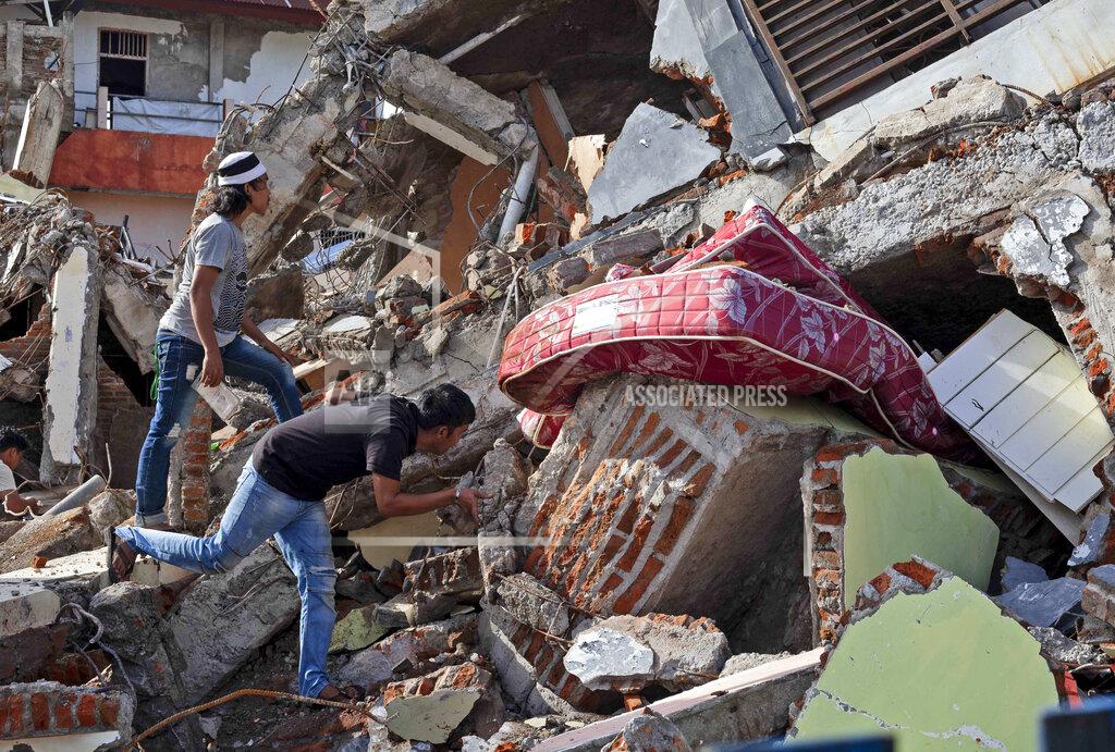 Yusuf Wahil Residents inspect a building collapsed in Friday's earthquake in Mamuju, West Sulawesi, Indonesia, Monday, Jan. 18, 2021. Aid was reaching the thousands of people left homeless and struggling after an earthquake that killed a number of people in the province where rescuers intensified their work Monday to find those buried in the rubble. (AP Photo/Yusuf Wahil)