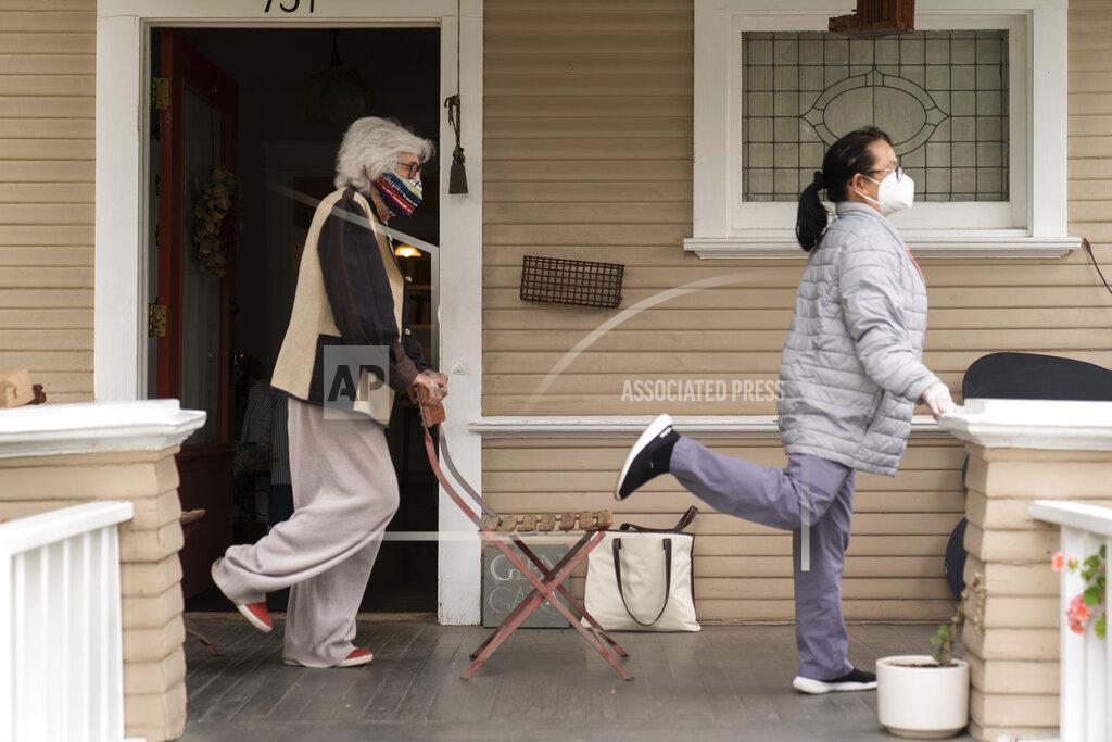 Damian Dovarganes Designer Gere Kavanaugh, left, wears a face mask of her design, as she exercises with Silver Age Home Health licensed vocational nurse Daisy Cabaluna during a weekly outdoors session at her home in the Echo Park neighborhood of Los Angeles, Monday, May 17, 2021. California is keeping its rules for wearing face masks in place until the state more broadly lifts its pandemic restrictions on June 15. (AP Photo/Damian Dovarganes)