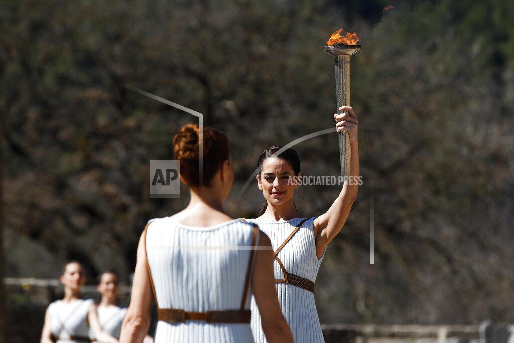 Thanassis Stavrakis Greek actress Xanthi Georgiou, playing the role of the High Priestess, holds up the torch during the flame lighting ceremony at the closed Ancient Olympia site, birthplace of the ancient Olympics in southern Greece, Thursday, March 12, 2020. Greek Olympic officials are holding a pared-down flame-lighting ceremony for the Tokyo Games due to concerns over the spread of the coronavirus. Both Wednesday's dress rehearsal and Thursday's lighting ceremony are closed to the public, while organizers have slashed the number of officials from the International Olympic Committee and the Tokyo Organizing Committee, as well as journalists at the flame-lighting. (AP Photo/Thanassis Stavrakis)