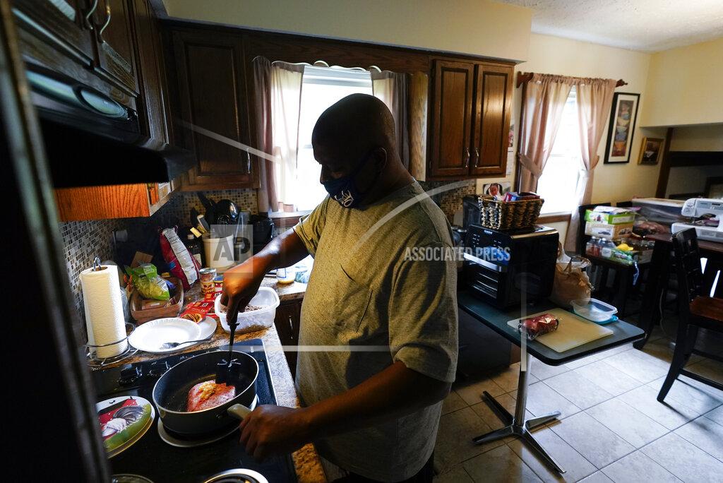 Darron Cummings Larry Brown cooks dinner at his parents house, Thursday, Aug. 27, 2020, in Indianapolis. Brown's has his kids chop ingredients so he can make favorite meals, meatloaf or baked mac and cheese. He's not yet comfortable gripping a knife, or even holding a pen like he used to. (AP Photo/Darron Cummings)