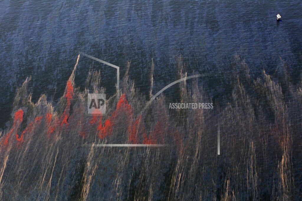 Eric Gay FILE - In this May 5, 2010 file photo, oil and oil sheen are seen moving past an oil rig, top right, in the waters of Chandeleur Sound, La. Ten years after an oil rig explosion killed 11 workers and unleashed an environmental nightmare in the Gulf of Mexico, companies are drilling into deeper and deeper waters where the payoffs can be huge but the risks are greater than ever. (AP Photo/Eric Gay, File)