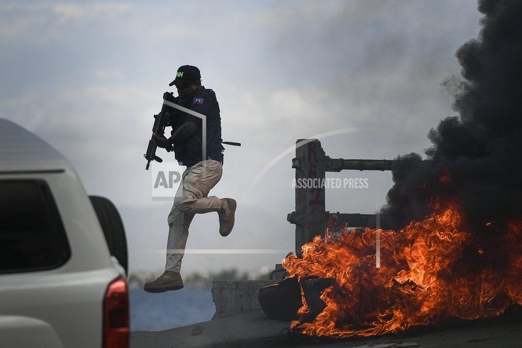 Matias Delacroix A police officer abandons his vehicle during a demonstration that turned violent in which protesters demanded justice for the assassinated President Jovenel Moise in Cap-Haitien, Haiti, Thursday, July 22, 2021. Demonstrations after a memorial service for Moise turned violent on Thursday afternoon with protesters shooting into the air, throwing rocks and overturning heavy concrete barricades next to the seashore as businesses closed and people took cover. (AP Photo/Matias Delacroix)