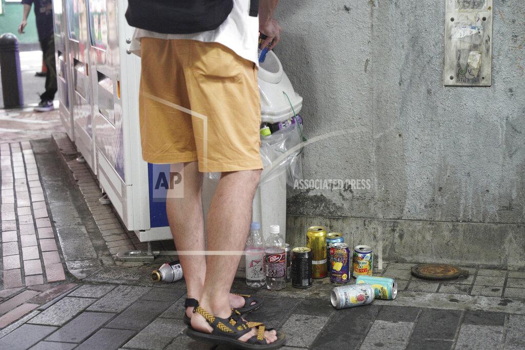 Kantaro Komiya A young man throws a beer can to already full garbage box in Tokyo’s Shinjuku district Monday, July 19, 2021. The latest state of emergency has asked restaurants and bars to close by 8 p.m., if not entirely. This has pushed people to drink outside, although many bars remain open and bustling with customers who are defying the rules and expressing frustration and indifference. (AP Photo/Kantaro Komiya)