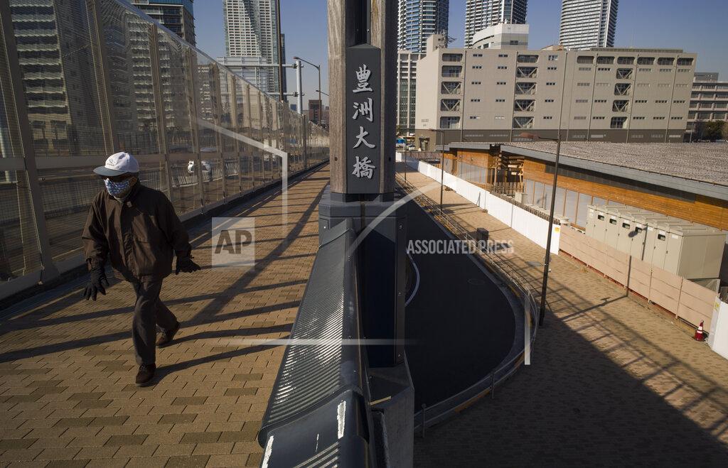 Hiro Komae A man walks on a bridge past a closed building complex, right, built to be used for the athletes' village during the rescheduled Tokyo Olympics, in Tokyo on Thursday, Jan. 21, 2021. The postponed Tokyo Olympics are to open in just six months. Local organizers and the International Olympic Committee say they will go ahead on July 23. But it’s still unclear how this will happen with virus cases surging in Tokyo and elsewhere around the globe. (AP Photo/Hiro Komae)