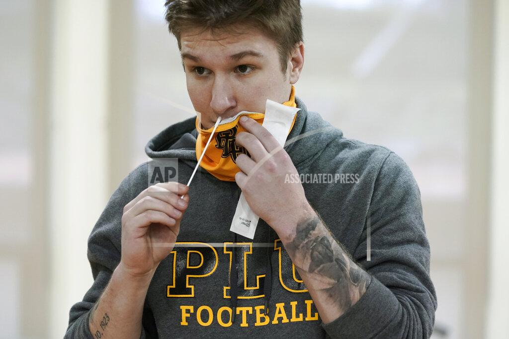 Ted S. Warren Tony Rath, a junior kicker at Pacific Lutheran, uses a nose swab to take a three-times-a-week COVID-19 test, Monday, Feb. 1, 2021, in Tacoma, Wash. Like the big programs that played in the fall, testing, distancing and protective equipment have topped the priority list in trying to pull off a season. (AP Photo/Ted S. Warren)