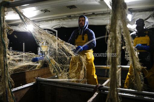 FILE - In this Thursday, Dec. 10, 2020 file photo, fisherman Nicolas Bishop works on the Boulogne sur Mer based trawler "Jeremy Florent II" in Boulogne-sur-Mer, northern France. The European Council adopted Tuesday, Sept. 28, 2021 a euro 5 billion (US dollar 5.8 billion) reserve aimed at helping businesses tackle the short-term negative effects of Brexit. Britain's departure has affected many parts of the EU economy, with the fishing sector particularly at risk. According to the European Commission, EU fisheries face a 25 percent reduction of their catch value in UK waters. (AP Photo/Michel Spingler, File)