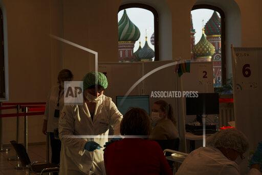 A medical worker administers a shot of Russia's Sputnik Lite coronavirus vaccine at a vaccination center in the GUM, State Department store, in Red Square with the St. Basil Cathedral in the background, in Moscow, Russia, Tuesday, Oct. 26, 2021. The daily number of COVID-19 deaths in Russia hit another high Tuesday amid a surge in infections that forced the Kremlin to order most Russians to stay off work starting this week. (AP Photo/Pavel Golovkin)