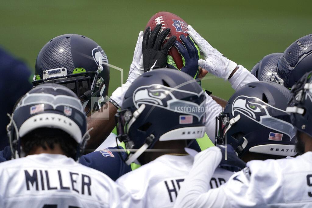 Ted S. Warren Seattle Seahawks defensive players touch the football during a huddle at NFL football practice Tuesday, June 15, 2021, in Renton, Wash. (AP Photo/Ted S. Warren)