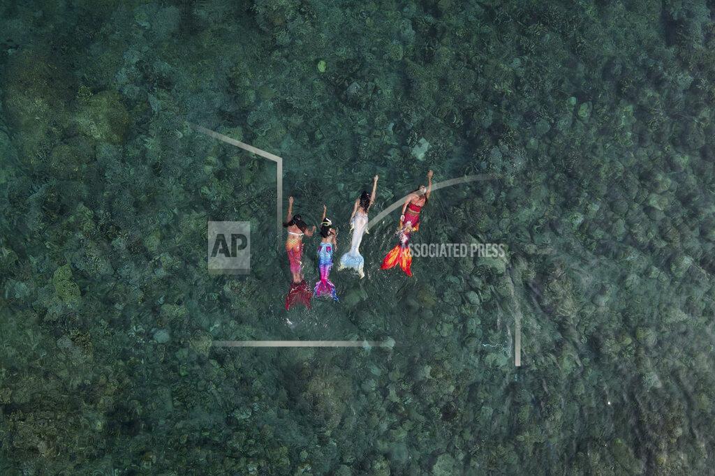 Aaron Favila Queen Pangke Tabora, right, swims with her students, from left, Shelah Candado, Jennica Secuya and Meryll Louise Reque, during a mermaiding class in Mabini, Batangas province, Philippines on Sunday, May 22, 2022. (AP Photo/Aaron Favila)