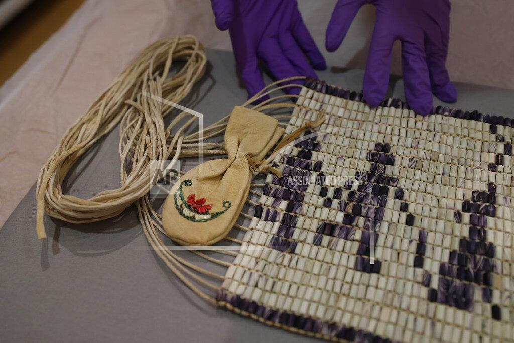 Alastair Grant Co-curator Jo Loosemore examines a recently created wampum belt made by members of the Wampanoag Native America people, after its unpacking and prior to it going on display in Southampton, England, Thursday, Aug. 13, 2020. On the 400th anniversary of the Mayflower voyage, commemorations are focusing on both the Pilgrim settlers and the Native people whose lives were transformed by their arrival. An exhibition in England focuses on one casualty of colonization: a wampum belt taken from the Wampanoag people to England in the 17th century, and then lost. (AP Photo/Alastair Grant)