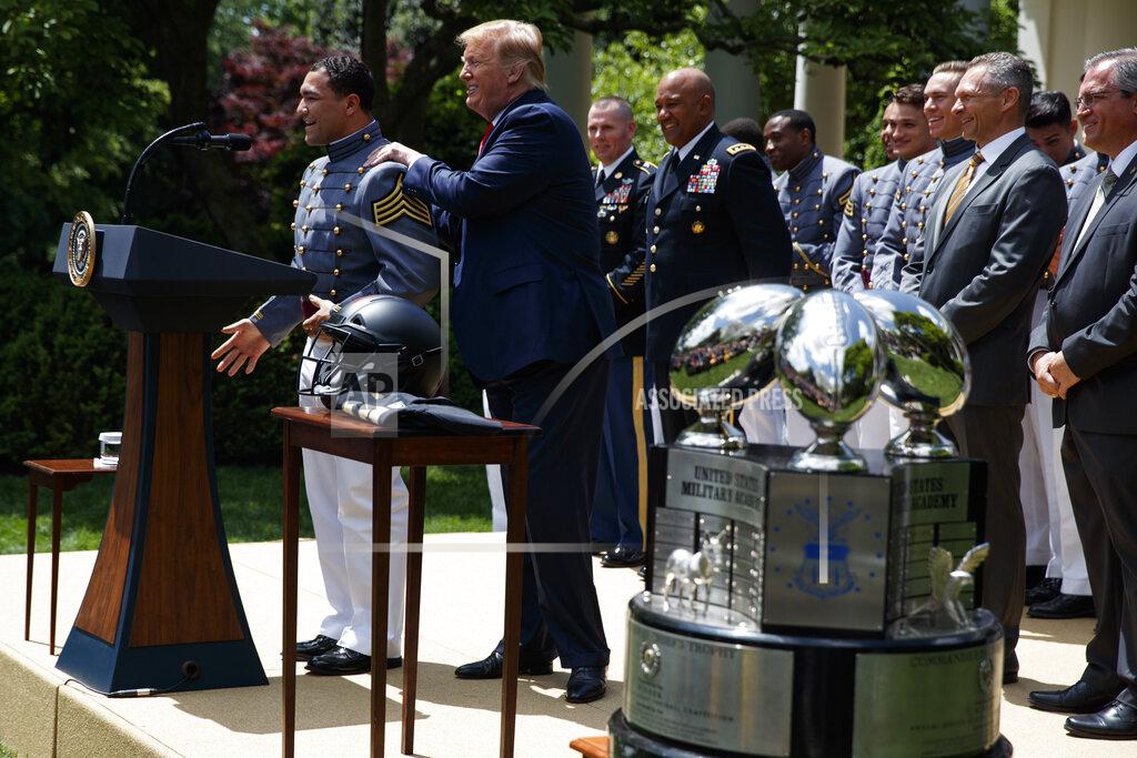 Evan Vucci President Donald Trump massages the shoulders of Army running back Darnell Woolfolk as he speaks during the presentation of the Commander-in-Chief's Trophy to the U.S. Military Academy at West Point football team, in the Rose Garden of the White House, Monday, May 6, 2019, in Washington. (AP Photo/Evan Vucci)