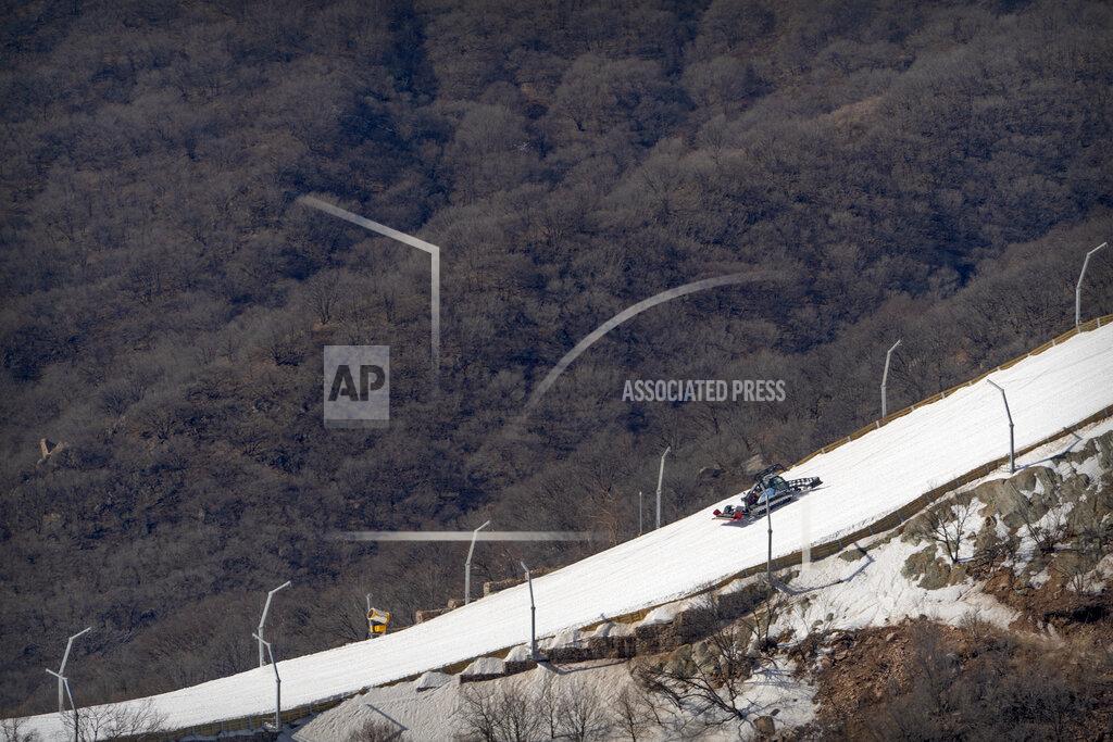Mark Schiefelbein A machine grooms a ski run lined with artificial snow at the National Alpine Skiing Center in Yanqing on the outskirts of Beijing, Friday, Feb. 5, 2021. Beijing Olympic organizers showed off the downhill skiing venue and the world's longest bobsled and luge track Friday, one year ahead of the scheduled opening of the 2022 Olympic Winter Games. (AP Photo/Mark Schiefelbein)