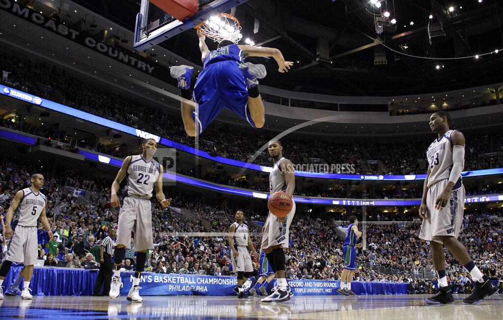 Matt Rourke FILE - In this March 22, 2013, file photo, Florida Gulf Coast's Chase Fieler (20) hangs from the rim after a dunk as Georgetown's Markel Starks (5), Otto Porter Jr. (22), D'Vauntes Smith-Rivera (4), Mikael Hopkins (3) and Aaron Bowen (23) look on during the second half of a second-round game of the NCAA college basketball tournament n Philadelphia. Florida Gulf Coast won 78-68. The Dunk City Effect, as it's called, accounted for a 35 percent increase in freshman applications following the NCAA run, boosted enrollment from about 13,000 to more than 15,000, and the academic reputation has been enhanced with higher caliber students being admitted. (AP Photo/Matt Rourke, File)
