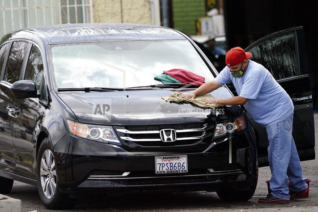 Marcio Jose Sanchez A worker wears a mask as he dries a car amid the COVID-19 pandemic at hand car wash shop Thursday, May 20, 2021, in Los Angeles. California regulators will shoot for a mid-June easing of workplace masking and social distancing requirements to conform with a broader state order. They asked to delay a debate Thursday on how quickly they should drop coronavirus safety rules for employees. (AP Photo/Marcio Jose Sanchez)