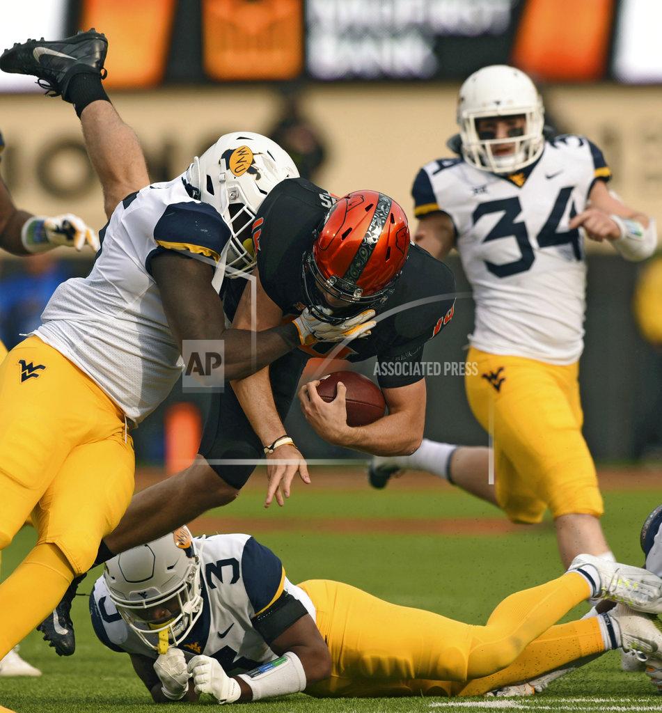 Brody Schmidt West Virginia linebacker Shea Campbell, right, watches as Oklahoma State quarterback Taylor Cornelius, center, jumps over West Virginia safety Toyous Avery Jr, down, while being tackled by defensive lineman Dante Stills during the first half of an NCAA college football game in Stillwater, Okla., Saturday, Nov. 17, 2018. Cornelius had 106 yards rushing in the 45-41 Oklahoma State upset over West Virginia.(AP Photo/Brody Schmidt)