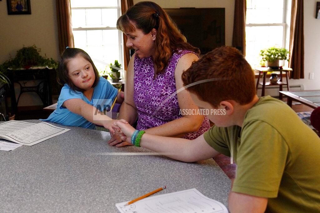 Charles Krupa Lily Osgood, 7, who has Down syndrome, shakes hands with brother, Noah, 12, right, after solving a problem while studying with their mother, Jennifer, at their home in Fairfax, Vt., on Tuesday, July 20, 2021. The Osgood children will continued to be homeschool this upcoming school year. As the pandemic took hold across the United States in the spring of 2020, it brought disruption and anxiety to most families. Yet some parents are grateful for one consequence: they are now opting to homeschool their children even as schools plan to resume in-person classes. (AP Photo/Charles Krupa)