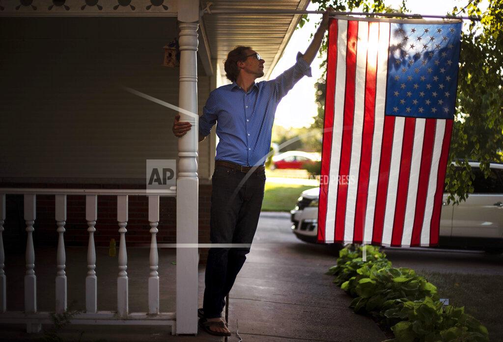 David Goldman Outagamie County Executive Tom Nelson adjusts the American flag hanging off his front porch in Appleton, Wis., Aug. 18, 2020. By his estimate, the county would have lost a catastrophic 2,000 jobs as collateral damage if the Midwest Paper Group mill closed. Nelson, the workers and their union representation lobbied the bankruptcy court and struck a deal. "If it were not for the fact that the mill was unionized, it would be a trash heap," Nelson said. (AP Photo/David Goldman)