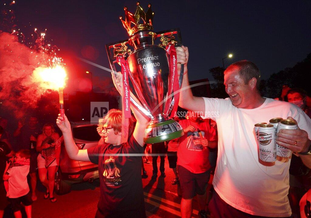 Jon Super Liverpool supporters hold a replica Premier League trophy as they celebrate outside of Anfield Stadium in Liverpool, England, Thursday, June 25, 2020 after Liverpool clinched the English Premier League title. Liverpool took the title after Manchester City failed to beat Chelsea on Wednesday evening. (AP photo/Jon Super)