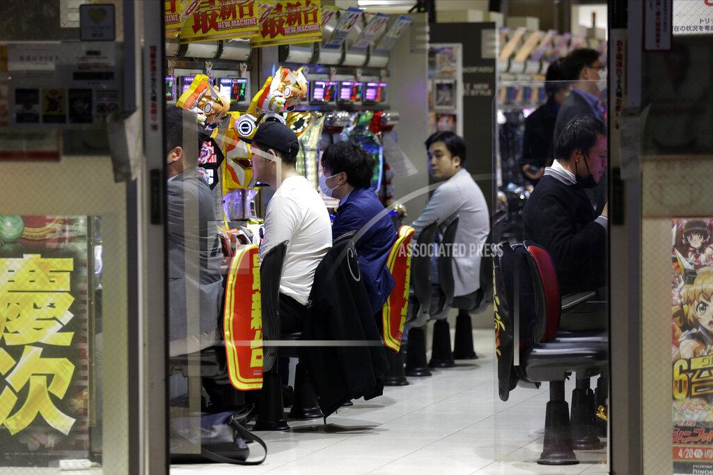 Kiichiro Sato In this April 24, 2020, photo, patrons play at a pachinko gaming parlor in Tokyo. Under Japan's coronavirus state of emergency, people have been asked to stay home. Many are not. Some still have to commute to their jobs despite risks of infection, while others are dining out, picnicking in parks and crowding into grocery stores with scant regard for social distancing. (AP Photo/Kiichiro Sato)
