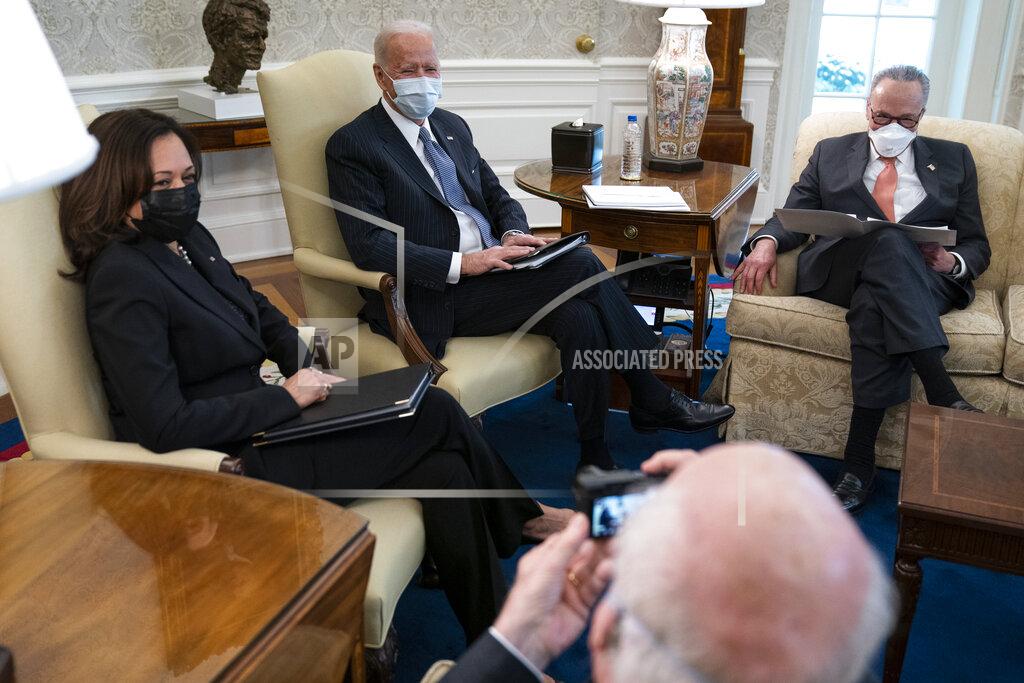 Evan Vucci Sen. Patrick Leahy, D-Vt., takes a photo of, from left, Vice President Kamala Harris, President Joe Biden, and Senate Majority Leader Sen. Chuck Schumer of N.Y., during a meeting to discuss a coronavirus relief package, in the Oval Office of the White House, Wednesday, Feb. 3, 2021, in Washington. (AP Photo/Evan Vucci)
