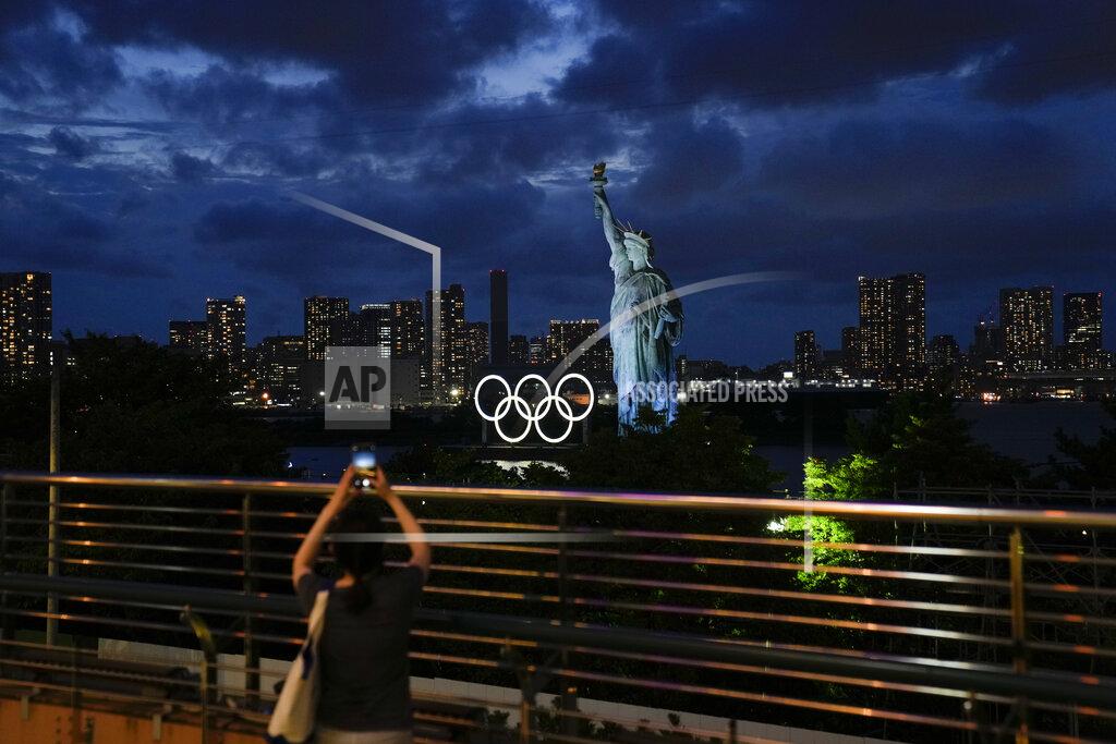 Jae C. Hong A woman takes pictures of the Olympic rings mounted on a barge floating in the water near a replica of the Statue of Liberty during the 2020 Summer Olympics, Thursday, July 29, 2021, in Tokyo, Japan. (AP Photo/Jae C. Hong)