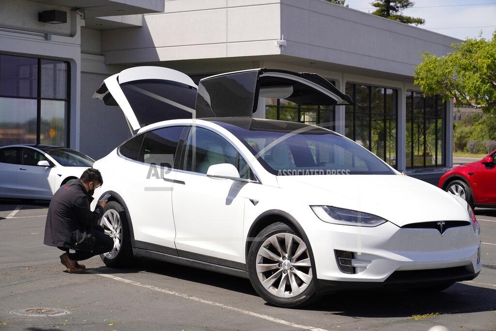 Eric Risberg A worker inspects a new electric car at a Tesla delivery location and service center Friday, April 2, 2021, in Corte Madera, Calif. The president and auto industry maintain the nation is on the cusp of a gigantic shift to electric vehicles and away from liquid-fueled cars, but biofuels producers and some of their supporters in Congress aren't buying it and argue now is the time to increase sales of ethanol and biodiesel, not abandon them. (AP Photo/Eric Risberg)