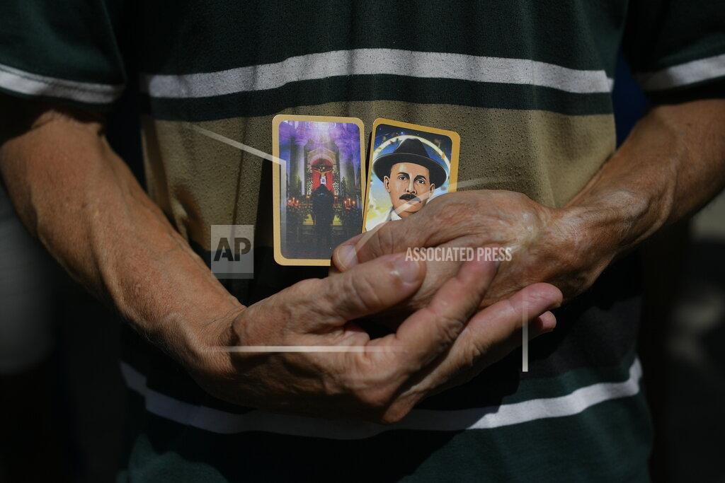 Matias Delacroix A man holds images of the late, Venezuelan Dr. Jose Gregorio Hernandez on the day of his Beatification ceremony outside the church that guards his remains in La Candelaria neighborhood of Caracas, Venezuela, Friday, April 30, 2021. Known as the "doctor of the poor, Hernandez will be beatified Friday by the Catholic church, a step towards sainthood. (AP Photo/Matias Delacroix)