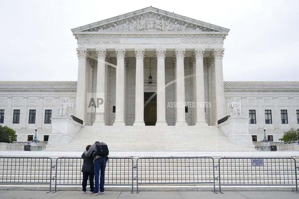 A woman and man pray outside the Supreme Court on Capitol Hill in Washington, Tuesday, Oct. 27, 2020, the day after the Senate confirmed Amy Coney Barrett to become a Supreme Court Justice. (AP Photo/Patrick Semansky)