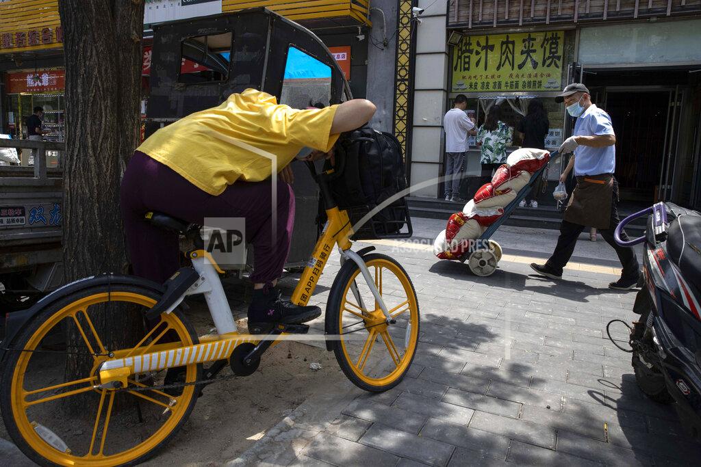 Ng Han Guan A delivery man wearing a mask to curb the spread of the coronavirus passes by a food stall in Beijing on Wednesday, July 1, 2020. Three months after China declared victory over the coronavirus and started to reopen its economy, restaurants are among thousands of small businesses that are struggling to lure back skittish consumers nervous about the virus and possible job losses. (AP Photo/Ng Han Guan)