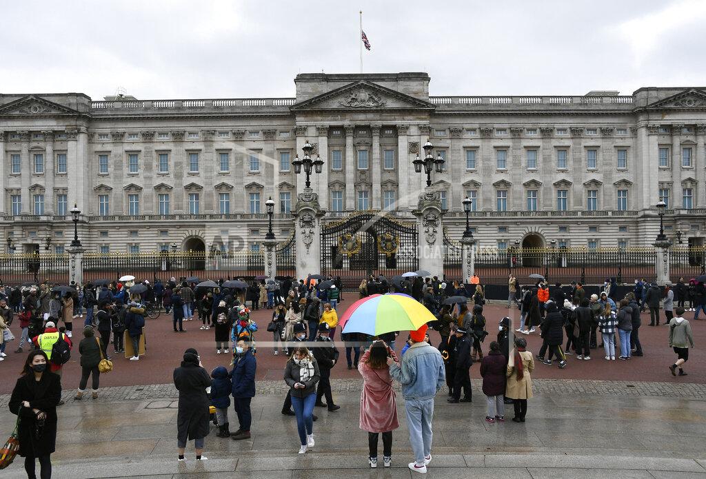 Alberto Pezzali A couple under an umbrella gather with others outside the gates at Buckingham Palace in London, a day after the death of Britain's Prince Philip, Saturday, April 10, 2021. Britain's Prince Philip, the irascible and tough-minded husband of Queen Elizabeth II who spent more than seven decades supporting his wife in a role that mostly defined his life, died on Friday. (AP Photo/Alberto Pezzali)