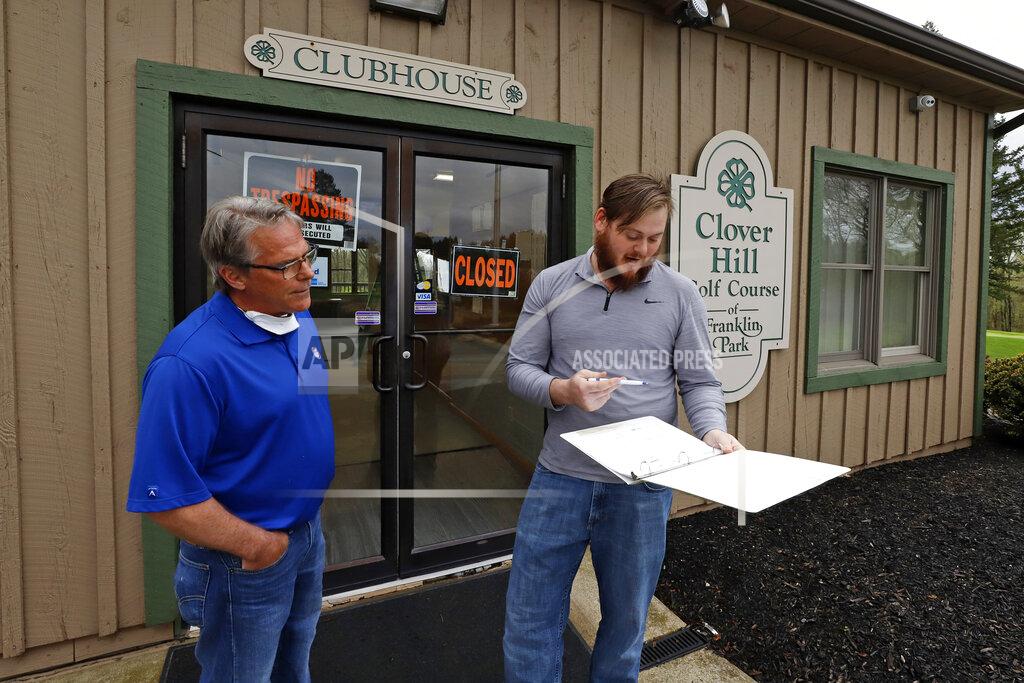 Clover Hill golf course manager Bill Schwietzer, left, and Josh Ford check tee-times outside the clubhouse on Thursday, April 30, 2020 in Pittsburgh. Golf courses across Pennsylvania are preparing to re-open Friday May 1, 2020, practicing safe-distancing to mitigate the spread of COVID-19. (AP Photo/Gene J. Puskar)