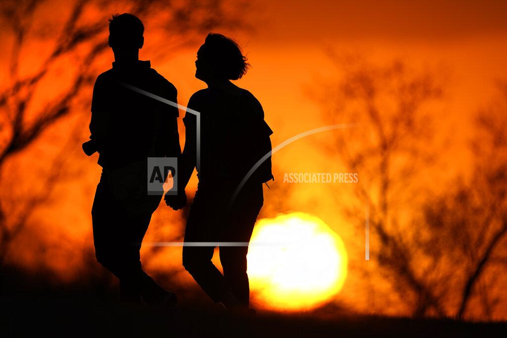 Charlie Riedel FILE - In this Wednesday, March 10, 2021 file photo, a couple walks through a park at sunset, in Kansas City, Mo. While most Americans have weathered the pandemic financially, about 38 million say they are worse off now than before the outbreak began in the U.S. According to a new poll from Impact Genome and The Associated Press-NORC Center for Public Affairs Research 55% of Americans say their financial circumstances are about the same now as a year ago, and 30% say their finances have improved. (AP Photo/Charlie Riedel, File)