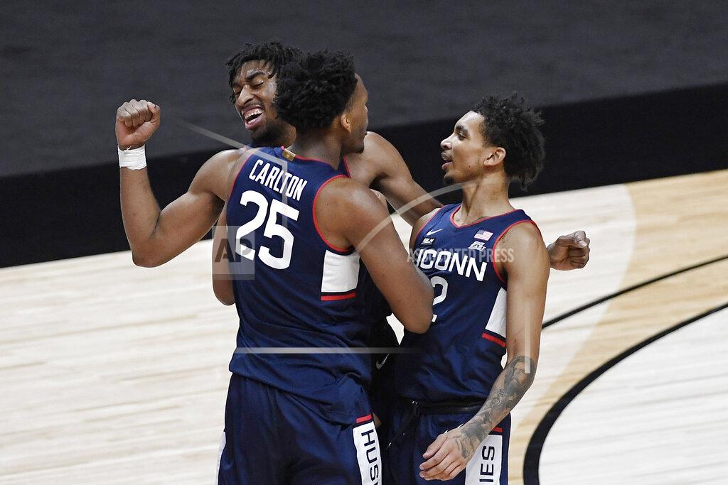 Jessica Hill Connecticut's Josh Carlton (25) celebrates with Isaiah Whaley, rear, and James Bouknight right, during the first half of an NCAA college basketball game against Southern California, Thursday, Dec. 3, 2020, in Uncasville, Conn. (AP Photo/Jessica Hill)