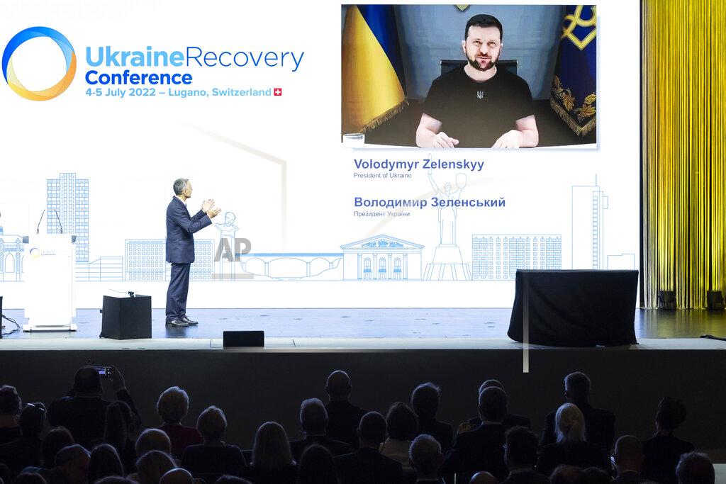 Michael Buholzer Swiss President Ignazio Cassis, Minister of Foreign Affairs, left, introduces Ukrainian President Volodymyr Zelenskyy delivering a speech by video conference during the Ukraine Recovery Conference URC, Monday, July 4, 2022 in Lugano, Switzerland. The URC is organised to initiate the political process for the recovery of Ukraine after the attack of Russia to its territory. (Michael Buholzer/Keystone via AP)
