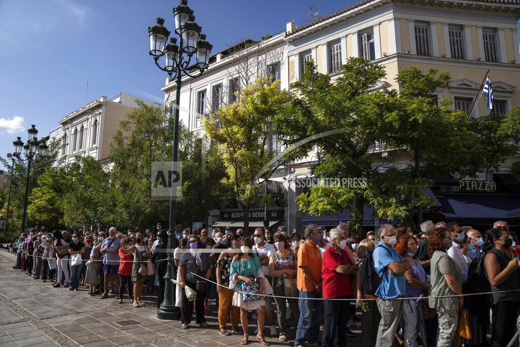 Petros Giannakouris People wait outside the Athens Cathedral to pay respects to the late Greek composer Mikis Theodorakis in Athens on Monday Sept. 6, 2021. Hundreds of people have gathered outside Athens Cathedral where Greek composer and politician Mikis Theodorakis is to lie in state in a chapel of the cathedral for three days ahead of his burial on the southern island of Crete. (AP Photo/Petros Giannakouris)