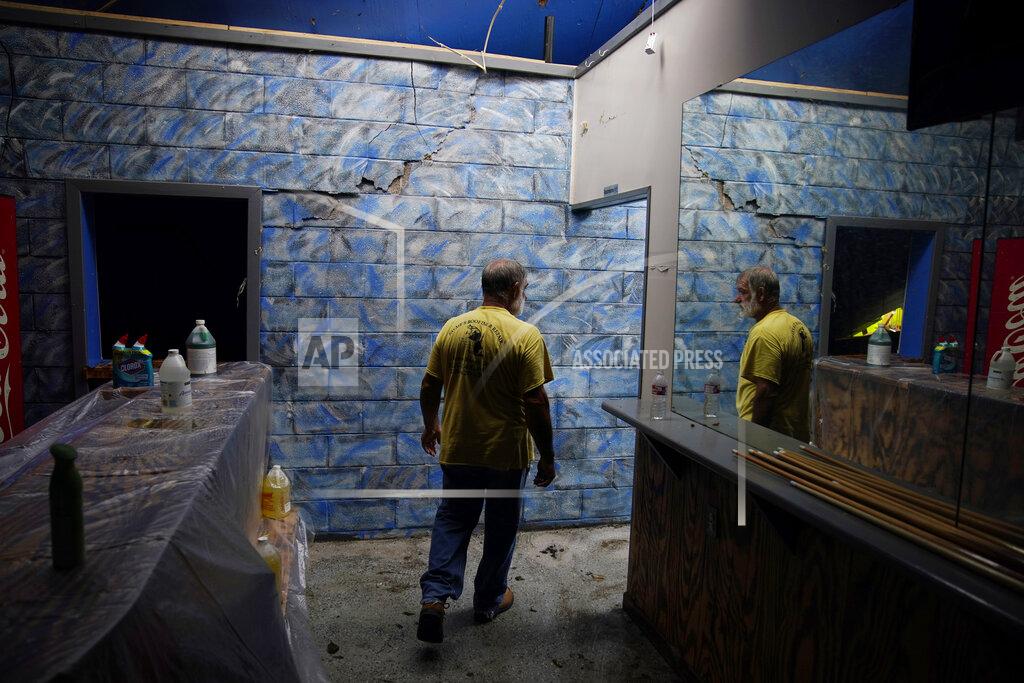 John Locher Daylight from a destroyed roof illuminates Blakland Matherne as he walks through his hurricane destroyed business in the aftermath of Hurricane Ida, Monday, Sept. 6, 2021, in Lockport, La. (AP Photo/John Locher)