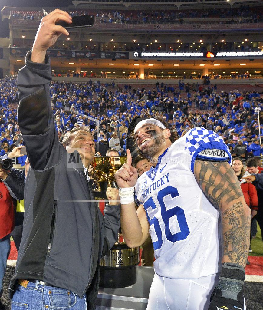 Timothy D. Easley Kentucky Gov. Matt Bevin, left, takes a selfie with Kentucky linebacker Kash Daniel (56) in front of the Governor's Cup following Kentucky's 56-10 victory over Louisville in an NCAA college football game, in Louisville, Ky., Saturday, Nov. 24, 2018. (AP Photo/Timothy D. Easley)