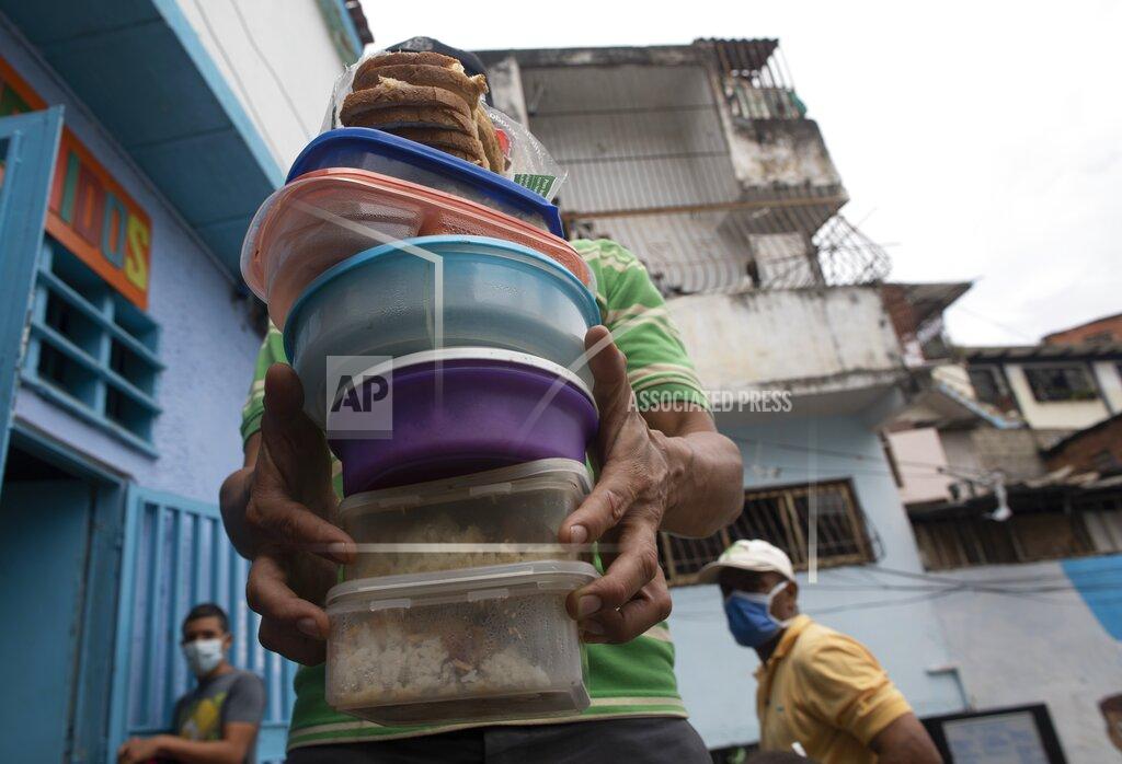 Ariana Cubillos A volunteer carries containers with rice, chicken and salad to be given to residents at the San Antonio de Padua soup kitchen in the Petare neighborhood of Caracas, Venezuela, Thursday, June 10, 2021, amid the new coronavirus pandemic. (AP Photo/Ariana Cubillos)