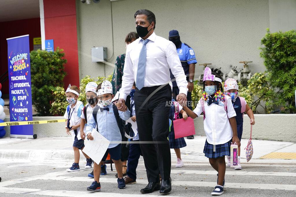 Lynne Sladky FILE- In this Aug. 23, 2021, file photo, Miami-Dade schools Superintendent Alberto Carvalho, center, walks with students Oliver Angel, left, and Ariah Olawale, right, outside of iPrep Academy on the first day of school, Monday, Aug. 23, 2021, in Miami. The on-again, off-again ban imposed by Republican Gov. Ron DeSantis to prevent mandating masks for Florida school students is back in force. The 1st District Court of Appeal ruled Friday, Sept. 10, 2021, that a Tallahassee judge should not have lifted an automatic stay two days ago that halted enforcement of the mask mandate ban. (AP Photo/Lynne Sladky, File)