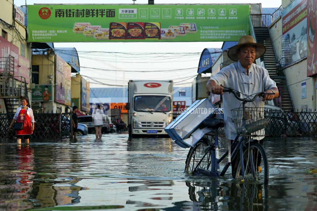 Dake Kang FILE - In this Monday, July 26, 2021 file photo, a man carries goods on his bicycle as he walks out of the the Yubei Agricultural and Aquatic Products World in Xinxiang in central China's Henan Province. Scientists say there’s something different this year from the recent drumbeat of climate weirdness. This summer a lot of the places hit by weather disasters are not used to getting extremes and many of them are wealthier, which is different from the normal climate change victims. That includes unprecedented deadly flooding in Germany and Belgium, 116-degree heat records in Portland, Oregon and similar blistering temperatures in Canada, along with wildfires. Now Southern Europe is seeing scorching temperatures and out-of-control blazes too. And the summer of extremes is only getting started. Peak Atlantic hurricane and wildfire seasons in the United States are knocking at the door. (AP Photo/Dake Kang, File)