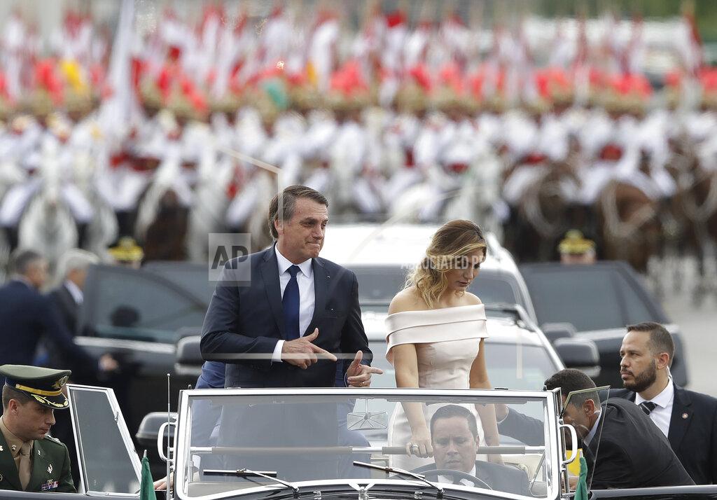 Andre Penner FILE - In this Jan. 1, 2019 file photo, Brazil's President Jair Bolsonaro points with his fingers to mimic guns as he rides in an open car with his wife, first lady Michelle Bolsonaro, after his swearing-in ceremony in Brasilia, Brazil. Bolsonaro’s pro-gun position was a trademark of his seven terms as a lower house lawmaker. In July 2018, he shocked adversaries by teaching a toddler how to make the finger-gun sign that came to represent his presidential campaign. (AP Photo/Andre Penner, File)