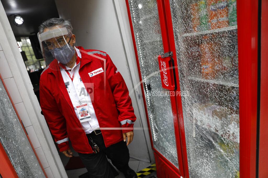 Rebecca Blackwell A gas station employee walks past drinks coolers that wereshattered during an attack by gunmen on police chief Omar Garcia Harfuch, in Mexico City, Friday, June 26, 2020. Heavily armed gunmen attacked and wounded Mexico City's police chief in an operation that left several dead. (AP Photo/Rebecca Blackwell)