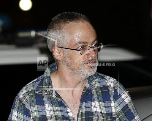 FILE - In this Aug. 19, 2017, file photo, Wyndham Lathem arrives at a police station as he is escorted by Chicago police in Chicago. A former Northwestern University professor is set to stand trial in the stabbing death of his boyfriend as part of what prosecutors said was a sexual fantasy he shared with another man who was charged in the case. Jury selection, opening statements and testimony from at least one witness were expected to happen Monday, Sept. 27, 2021 in the trial of 47-year-old Wyndham Lathem. (AP Photo/Jim Young, Pool, File)